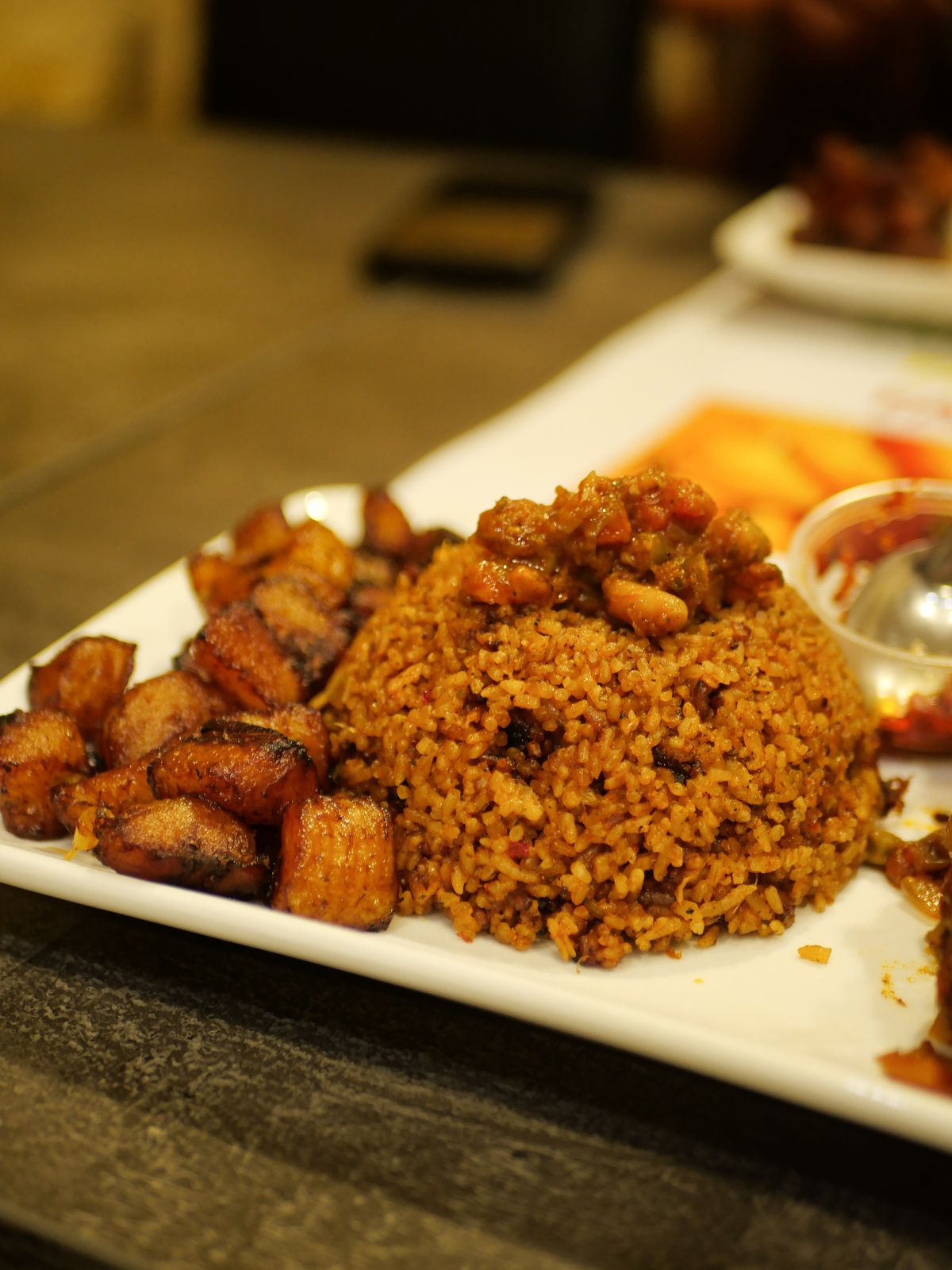A plate of smoky jollof rice with golden fried plantain