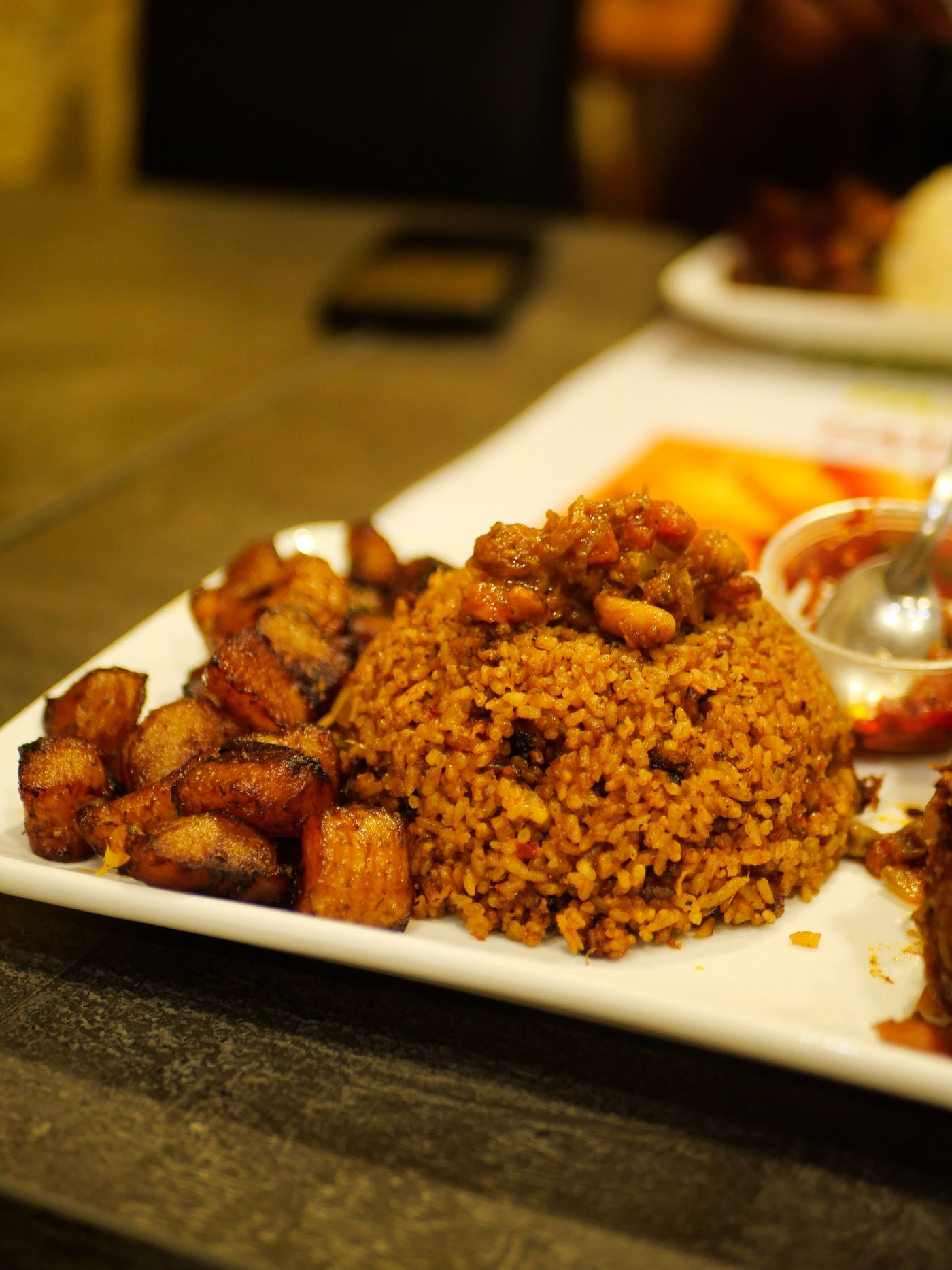 Jollof rice with golden fried plantain on a white plate
